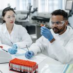 Dois pesquisadores analisam amostras e registram dados em um laboratório clínico.