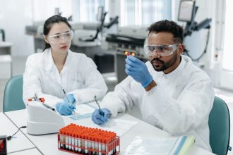 Dois pesquisadores analisam amostras e registram dados em um laboratório clínico.