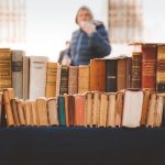 Livros antigos expostos em uma banca de mercado ao ar livre.