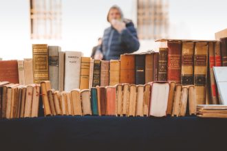 Livros antigos expostos em uma banca de mercado ao ar livre.