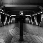 Estação de metrô moderna, em preto e branco, com um posto de telefone de emergência em destaque.