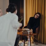 Autor participa de uma conversa literária em ambiente interno diante de leitores.