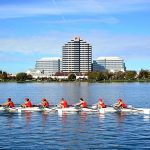 Equipe de remo com oito atletas competindo em uma regata na água.